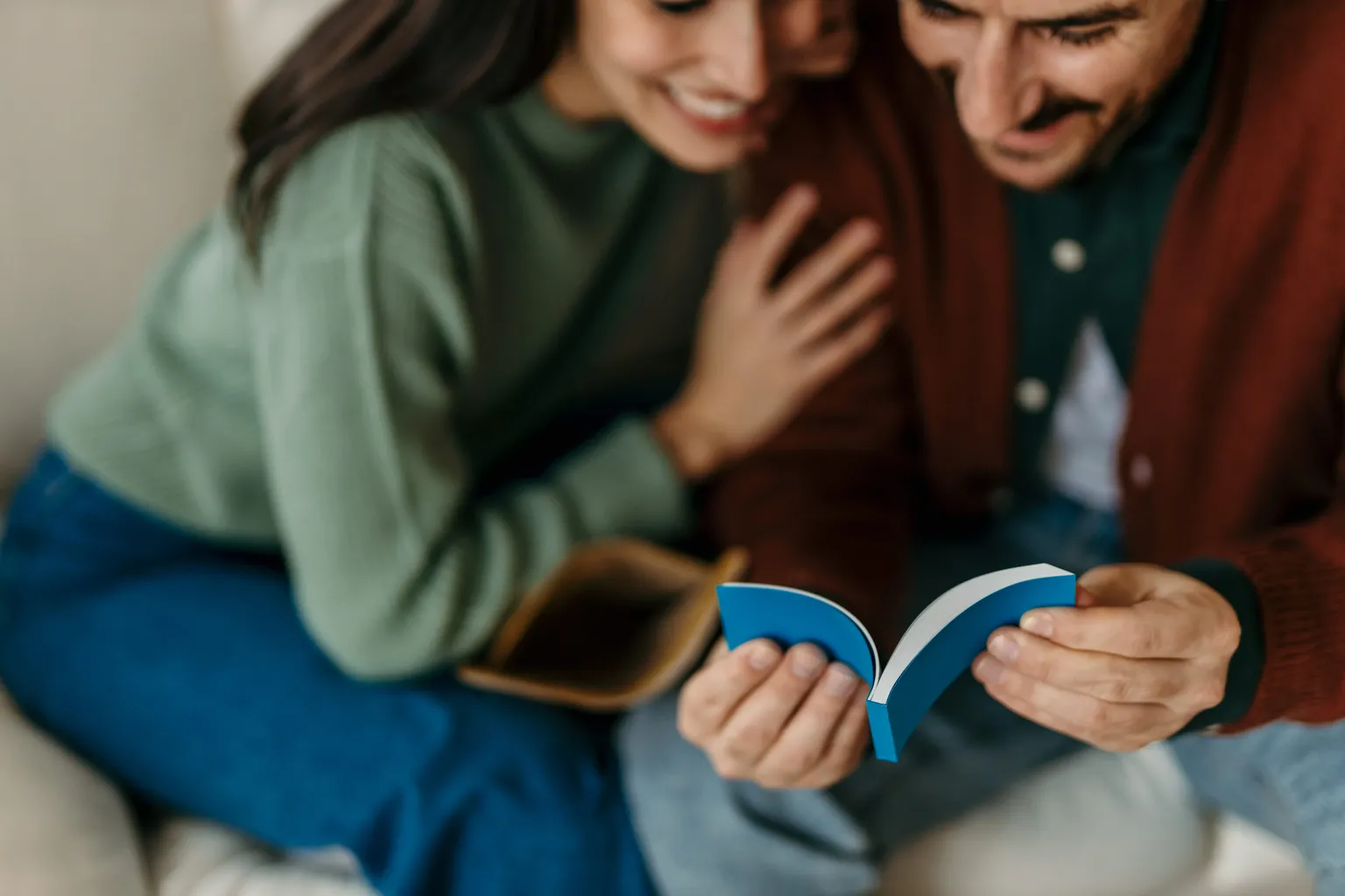 Happy couple laughing together while flipping through a custom flipbook gift on the couch